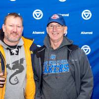 Two people standing in front of GV Alumni backdrop, smiling for photo